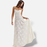 Modelo veste vestido maxi branco El Armario de Lola com alças finas, corte justo e padrão floral subtil em tecido sedoso